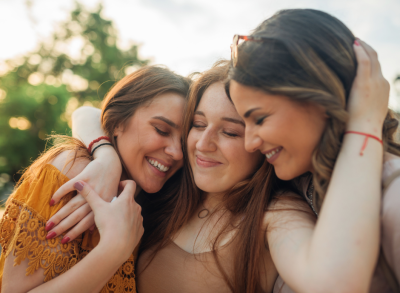 Smiling woman squeezing two friends closely.