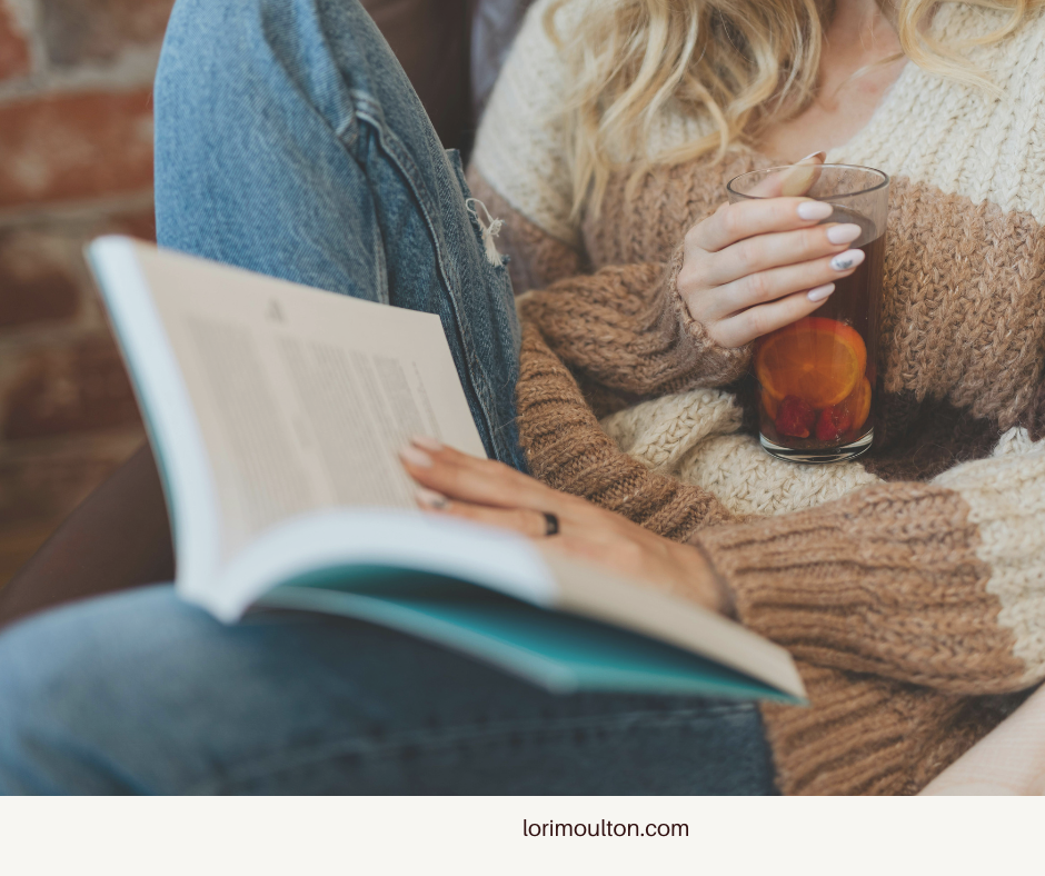 Woman holding a glass of tea and reading a book.